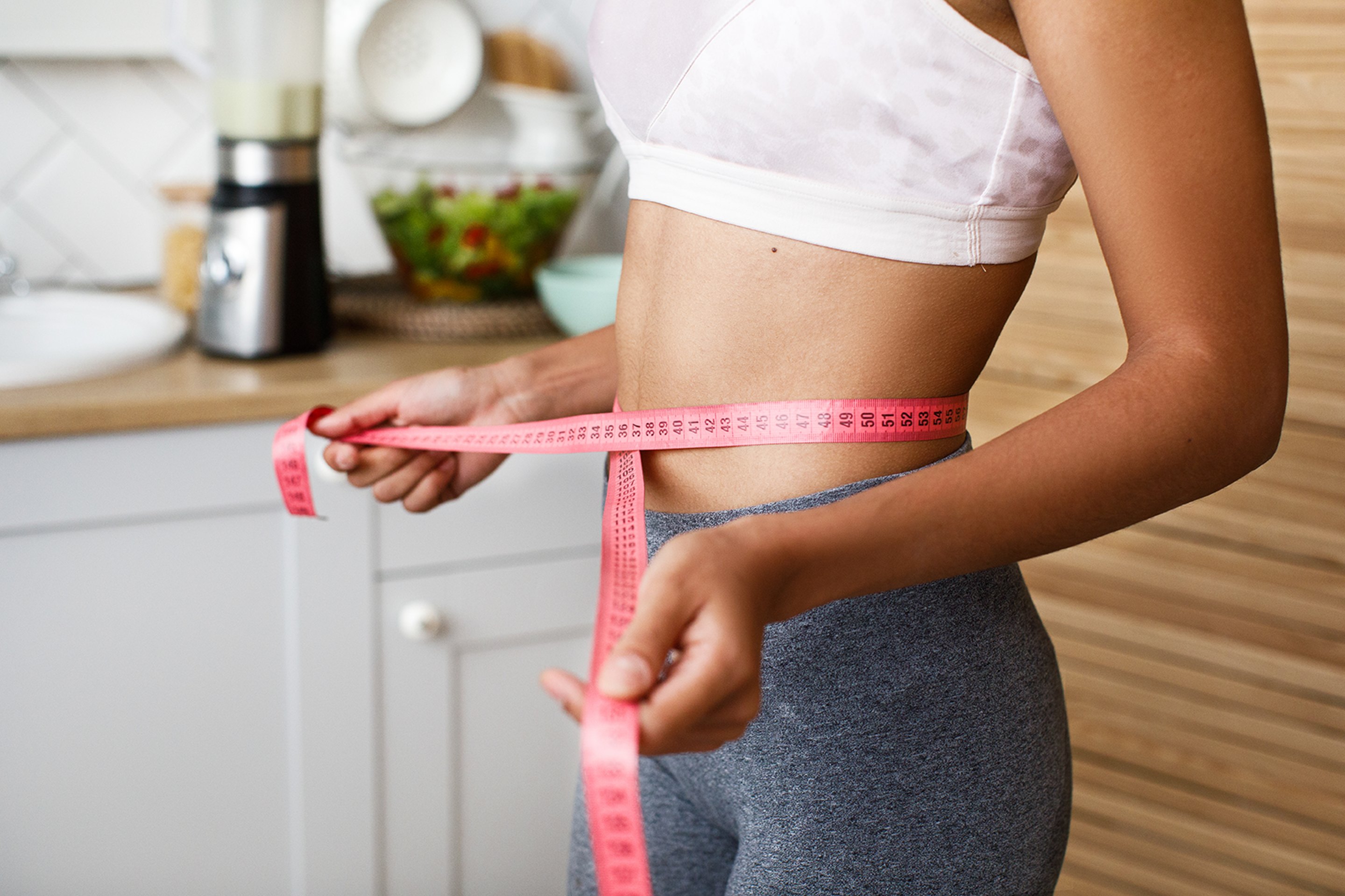 A young woman measuring her waist during metabolic testings.
