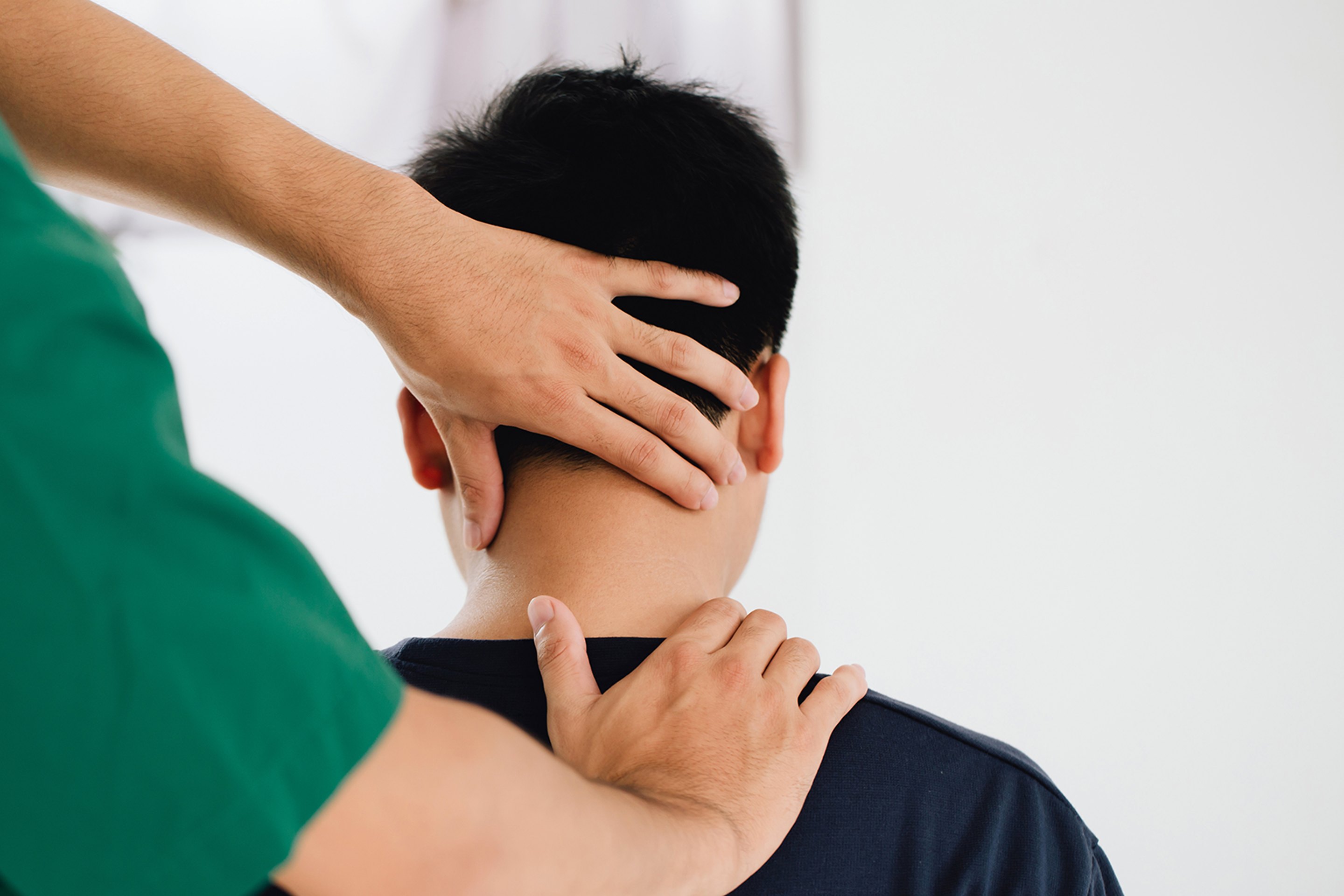 A chiropractor giving a neck adjustment to a male patient.