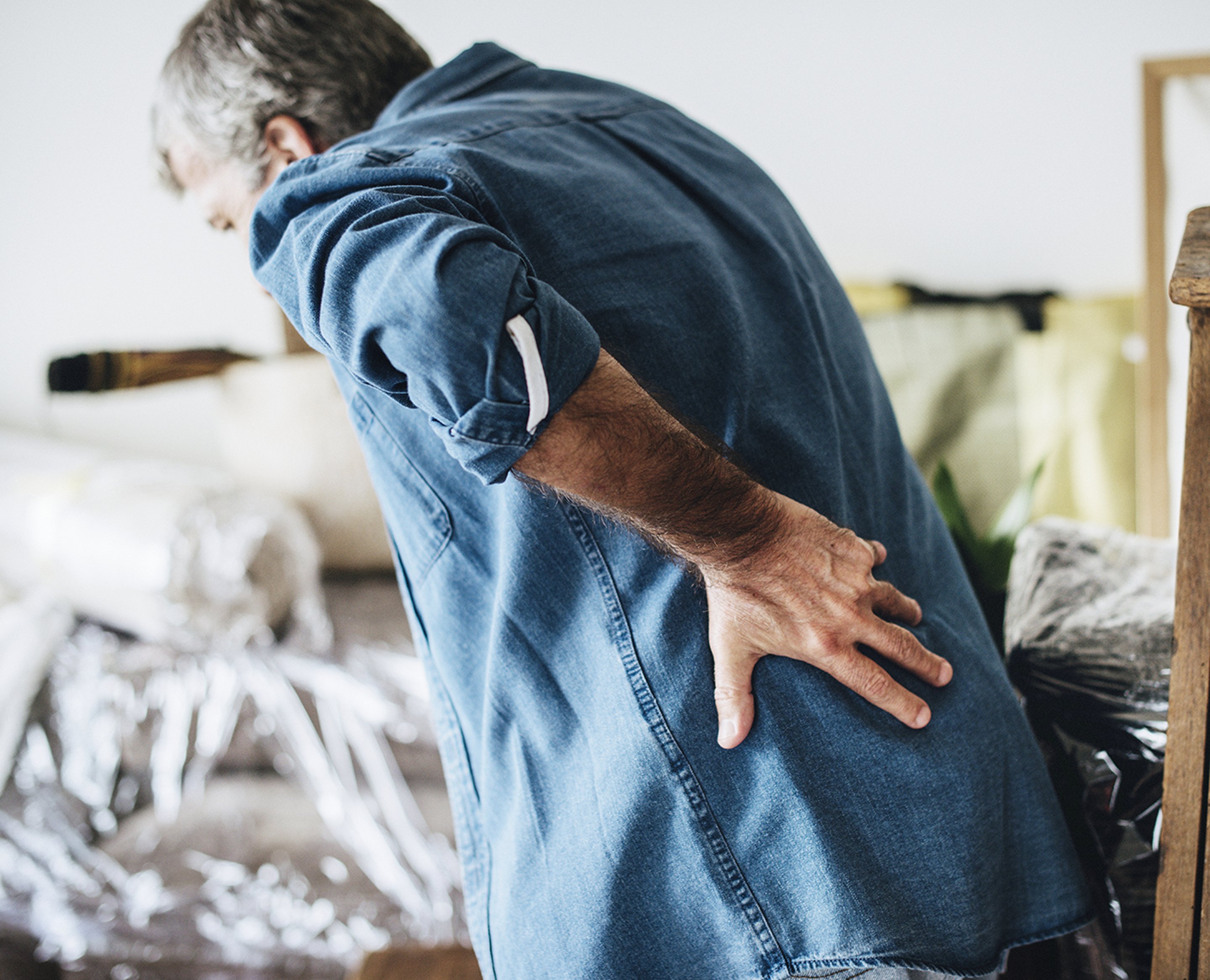 A man with sciatica holding his painful lower back.