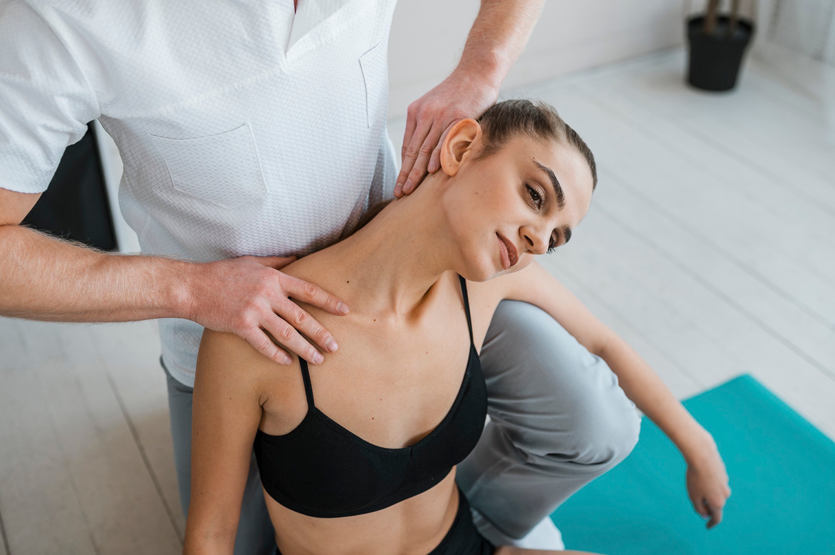 A sports chiropractor treating a female athlete's neck and shoulder.