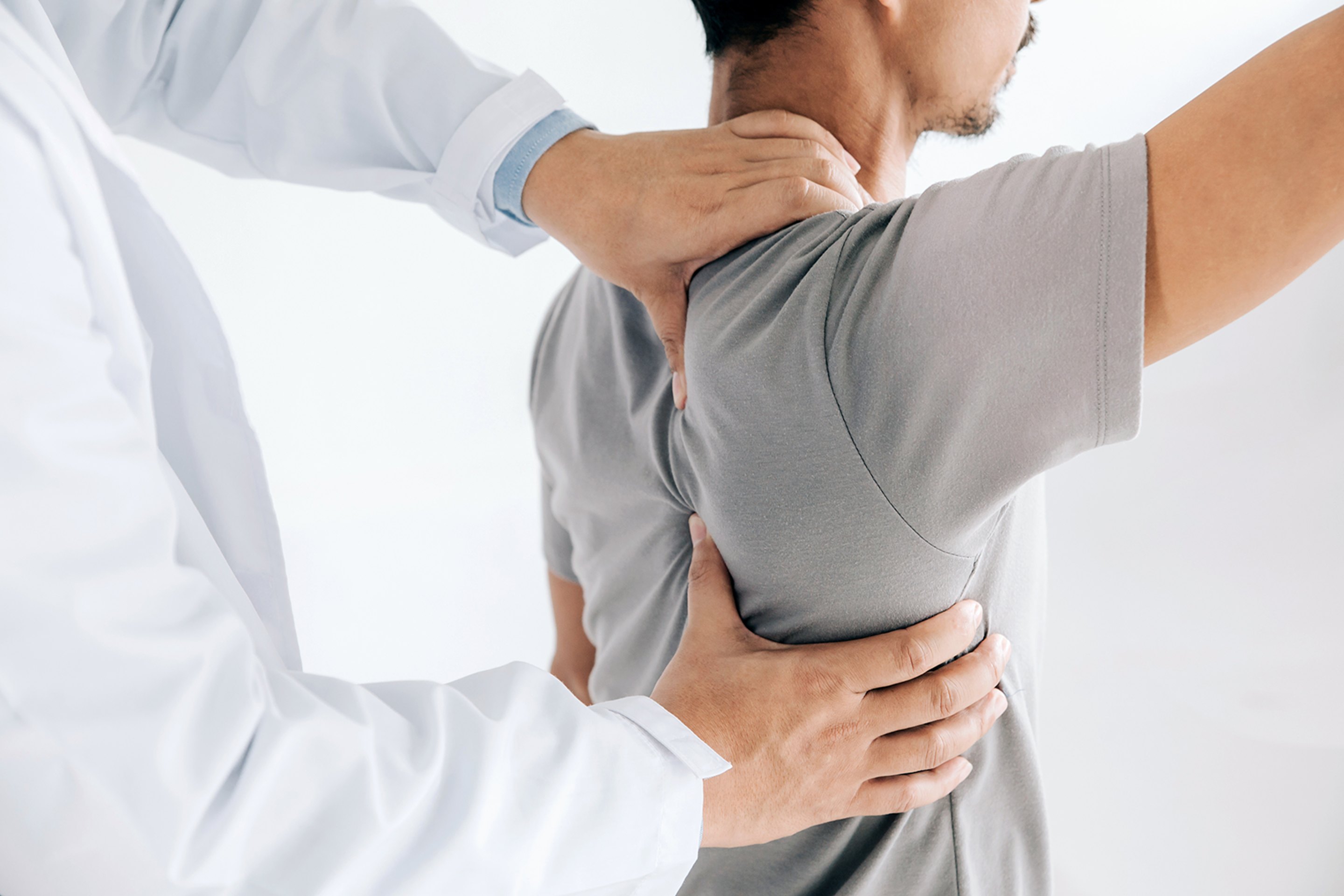A medical professional performing a back adjustment on a male patient.