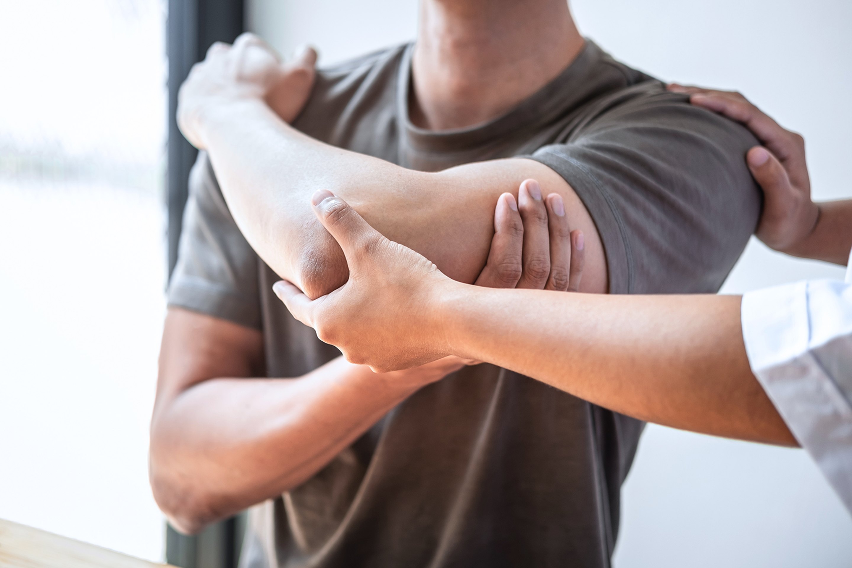A male patient receiving a shoulder adjustment from a sports chiropractor.