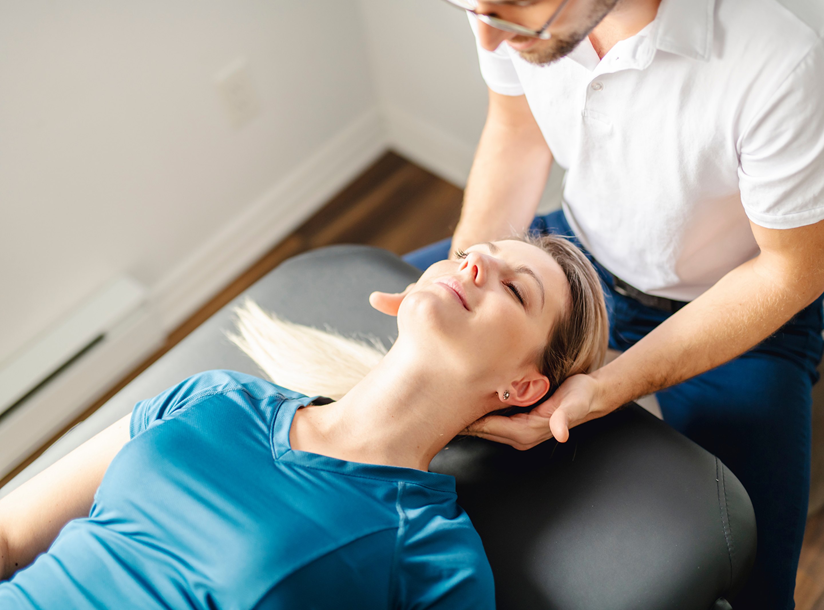 A male chiropractor treating a female patient's neck after a sports injury.