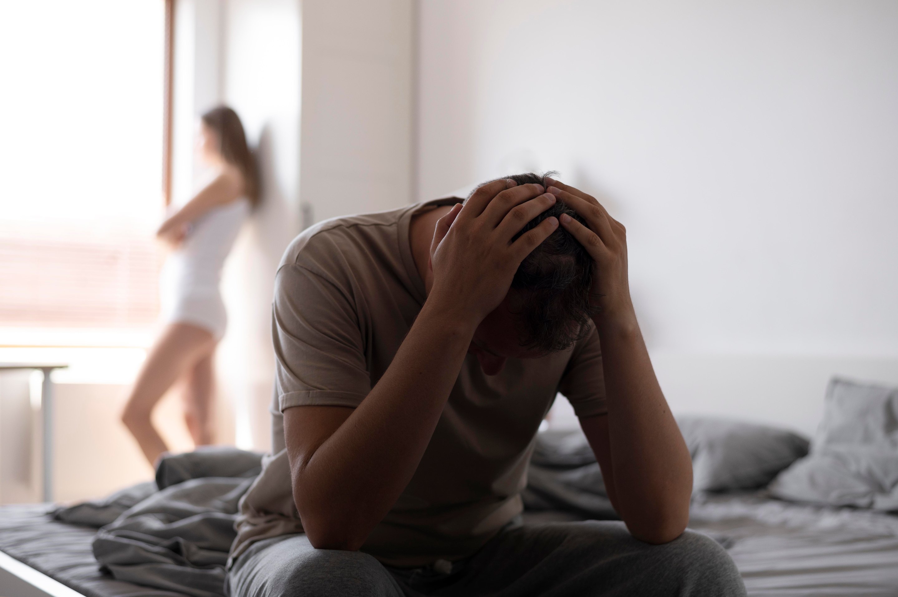 A frustrated man sitting on a bed, due to sexual health issues in Stuart, FL.