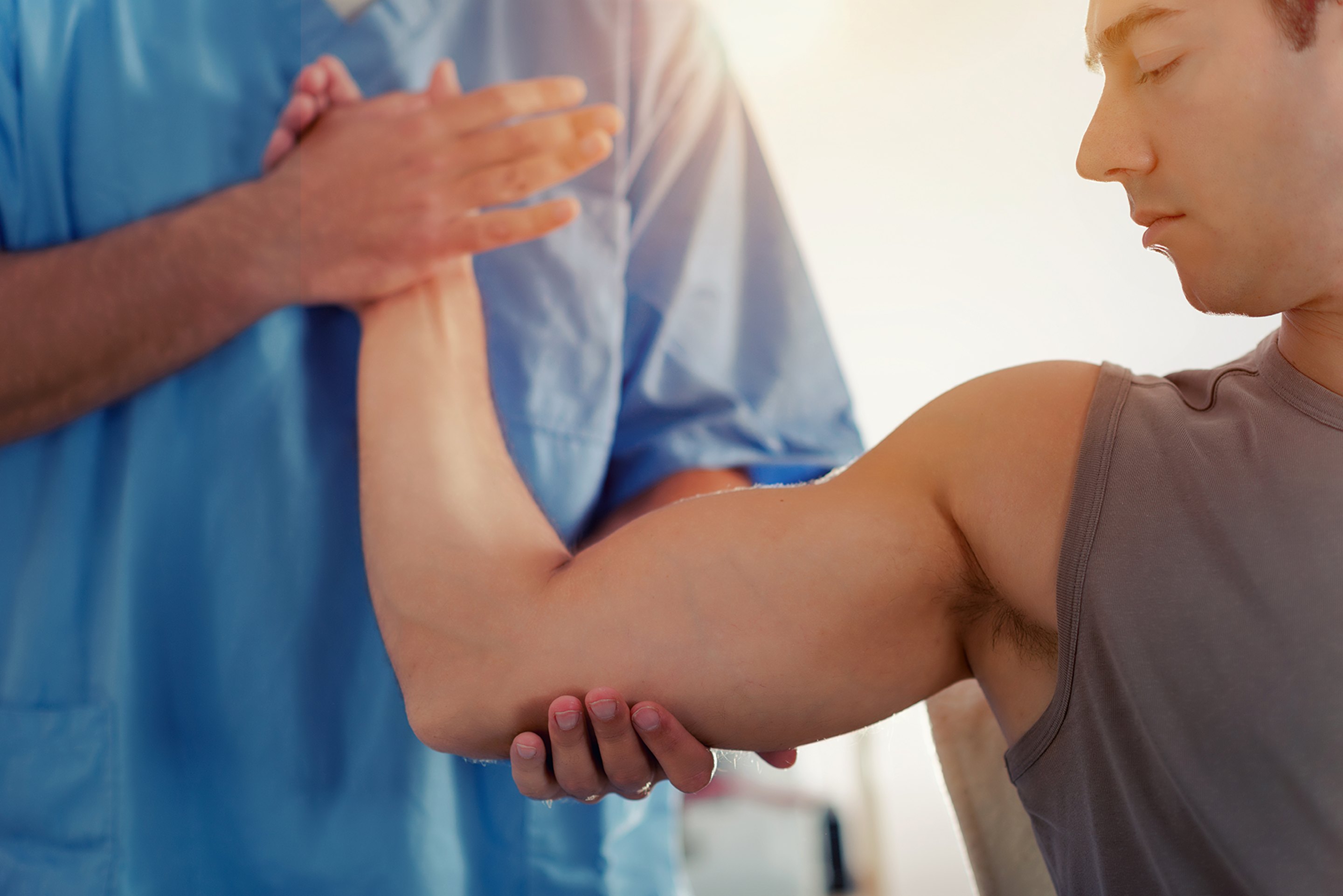 A chiropractor treating a patient's elbow or shoulder for joint pain.
