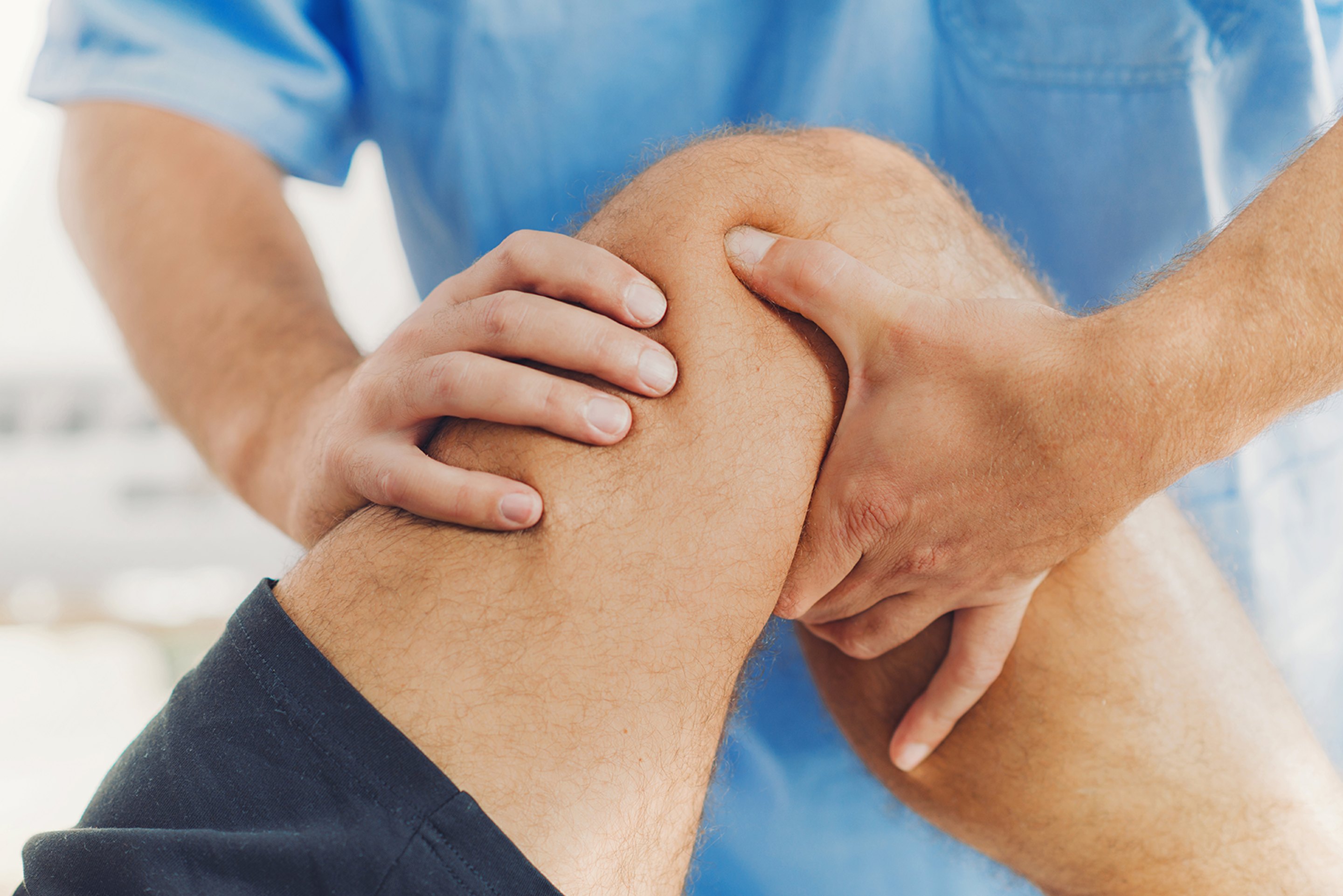 A chiropractor or physical therapist treating a patient's knee.