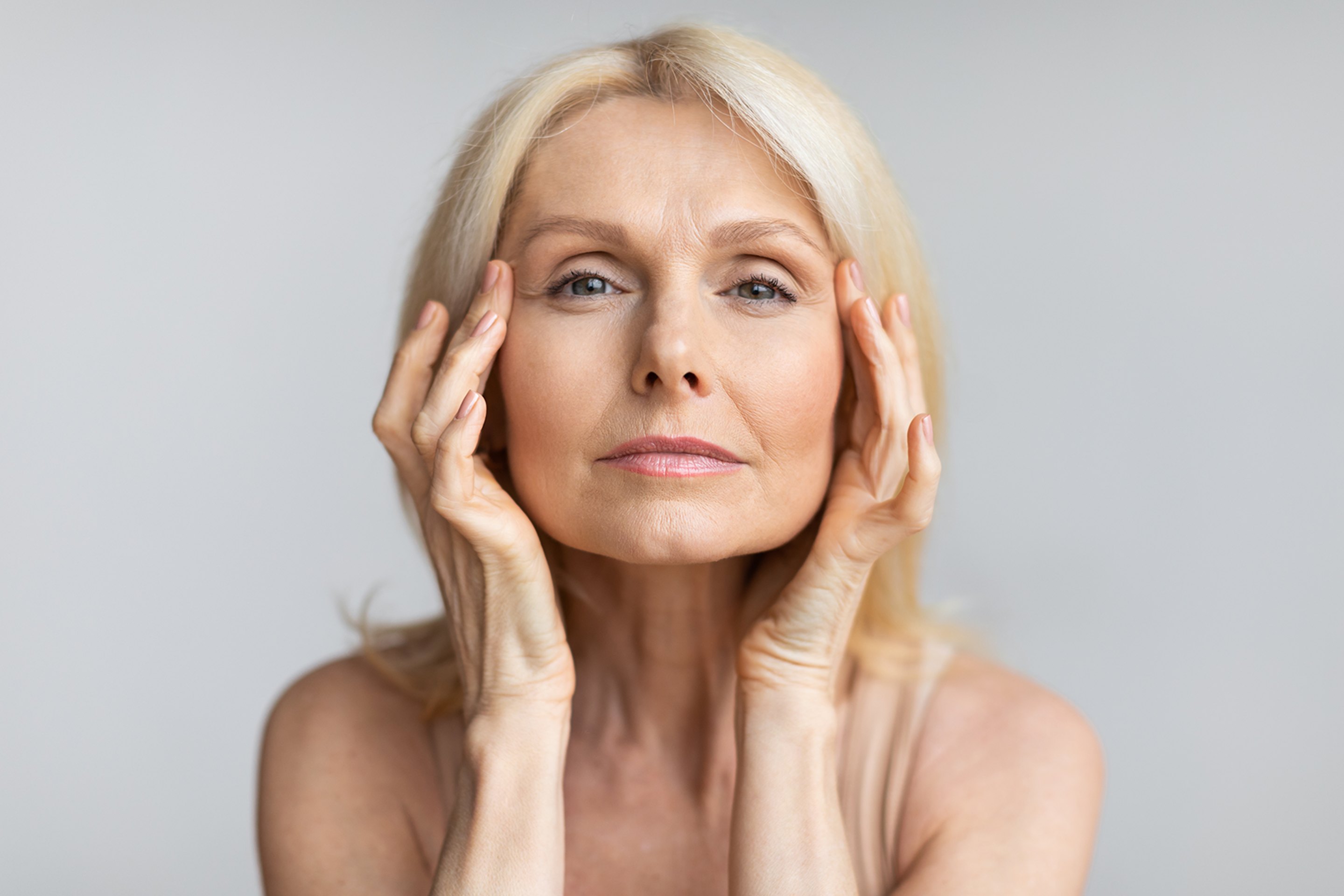 A serene, middle-aged woman with youthful skin thanks to peptide therapy.